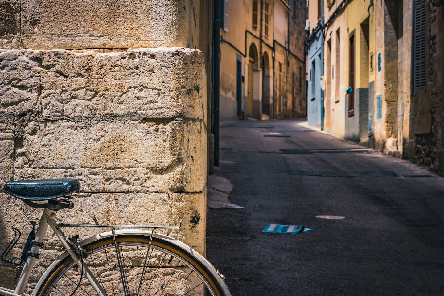 Bicicletta bianca vintage parcheggiata contro un muro di pietra grezza.