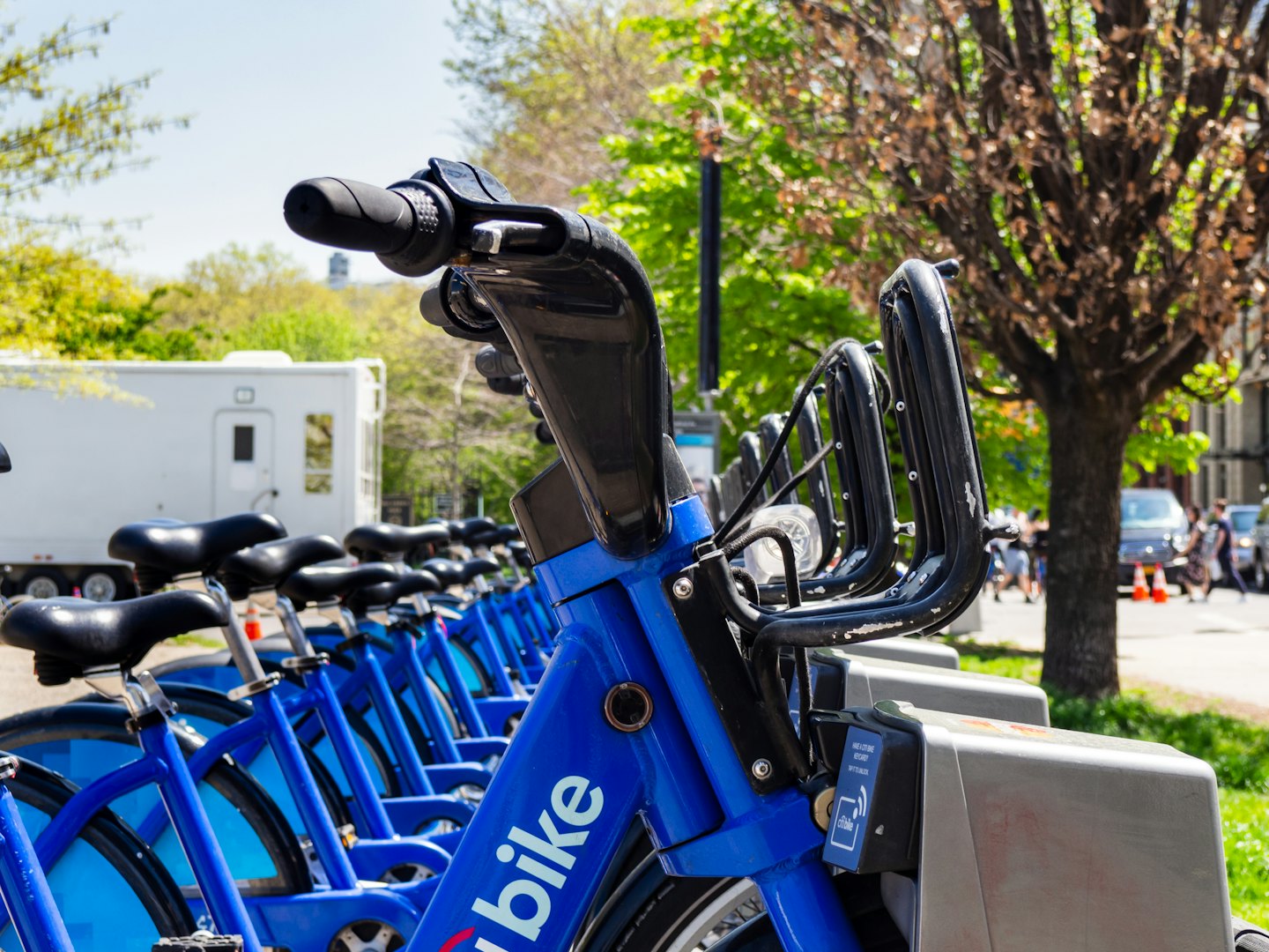 Biciclette blu a noleggio allineate in una stazione all'aperto.